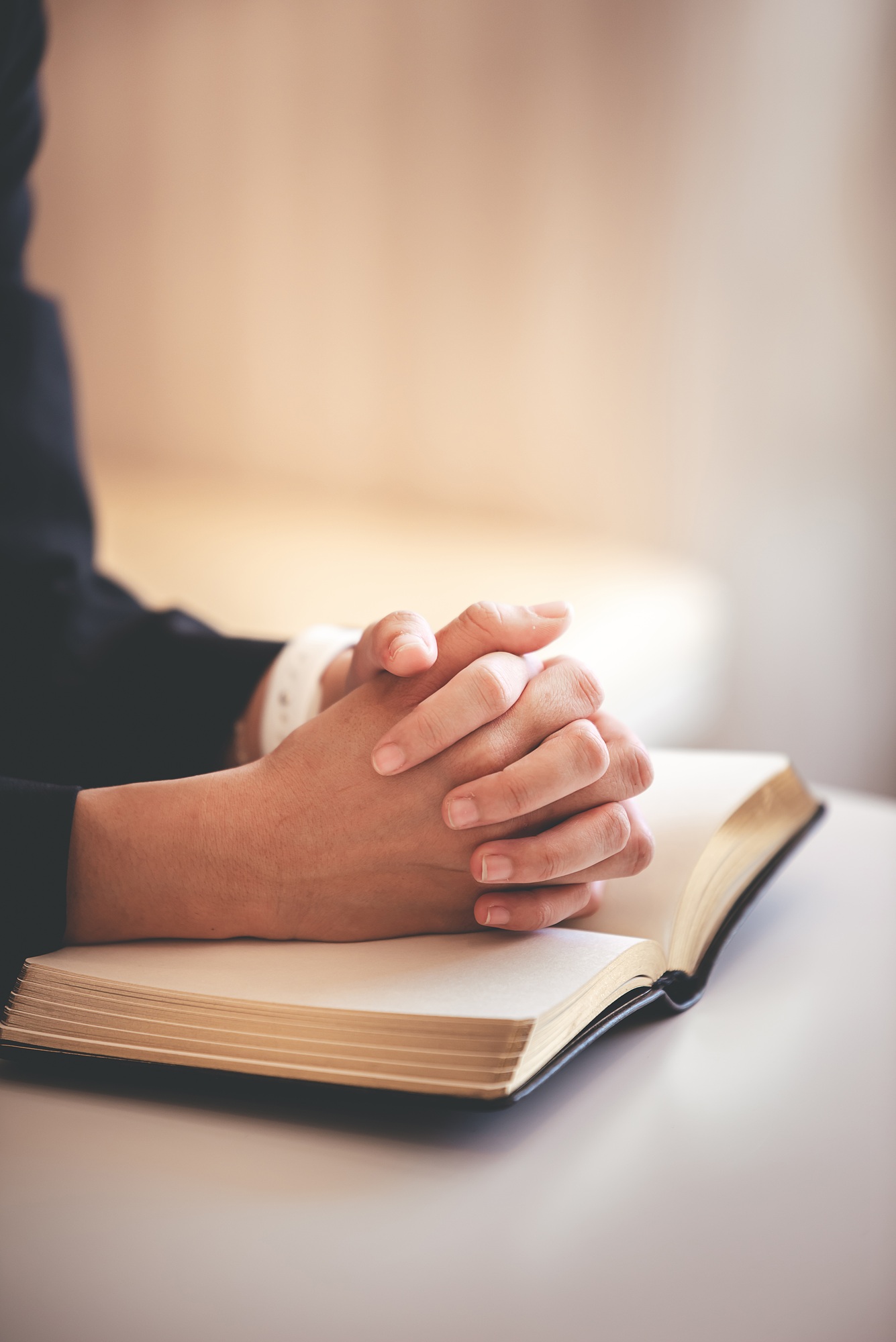 focus on woman's hand While praying for Christianity with blurry body background, casual woman prays